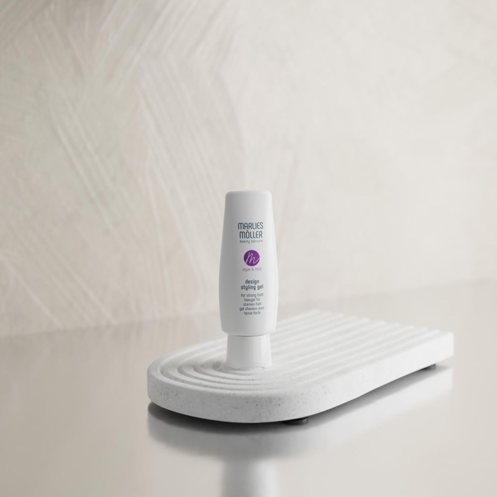 Eine weiße Tube Marlies Möller Design Styling Hair Gel auf einem weißen, gerippten Ständer.