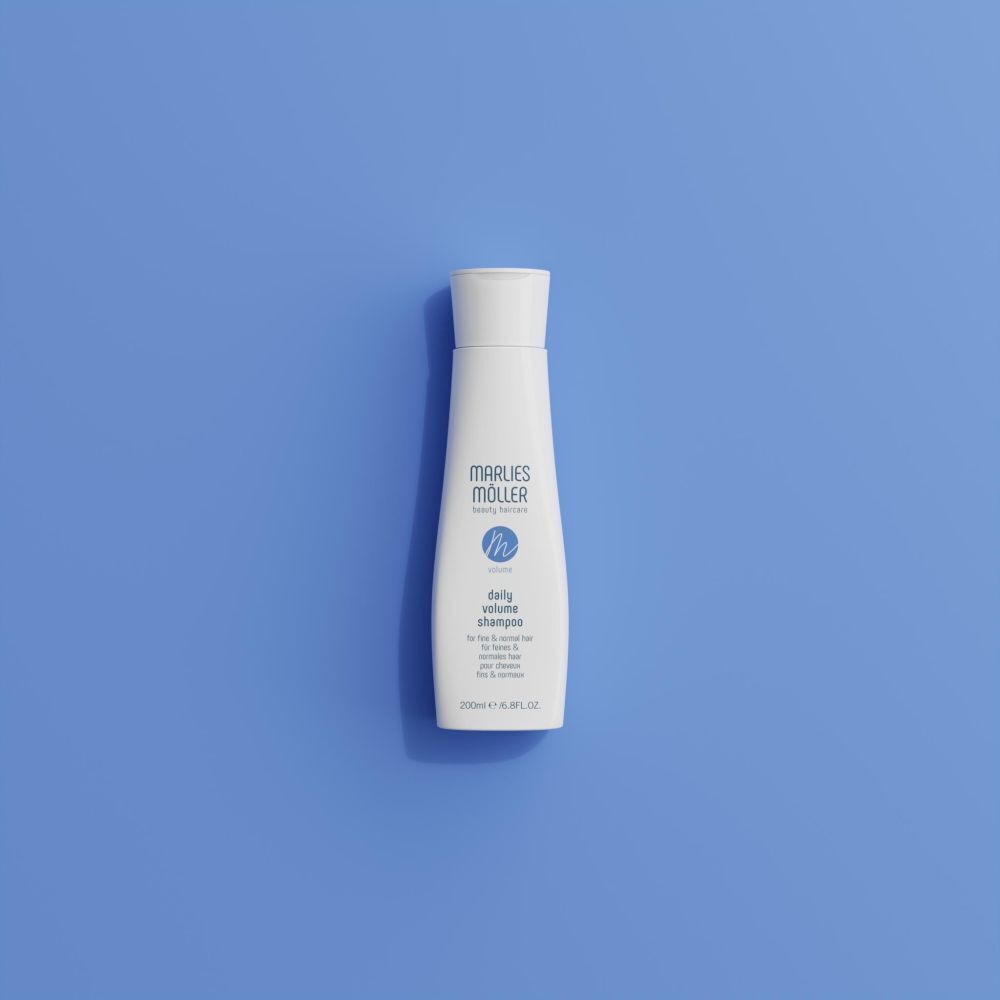 Un flacon blanc de Marlies Möller Daily Volume Shampoo sur fond bleu.