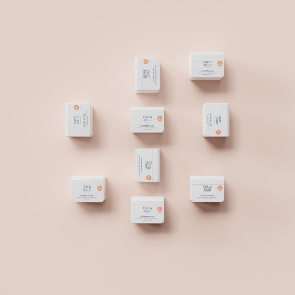 Mehrere Produkte auf rosa Hintergrund. Weiße Dosen mit Produktbezeichnung. Schriftzug: Marlies Möller, overnight hair mask. Orangefarbenes Logo.