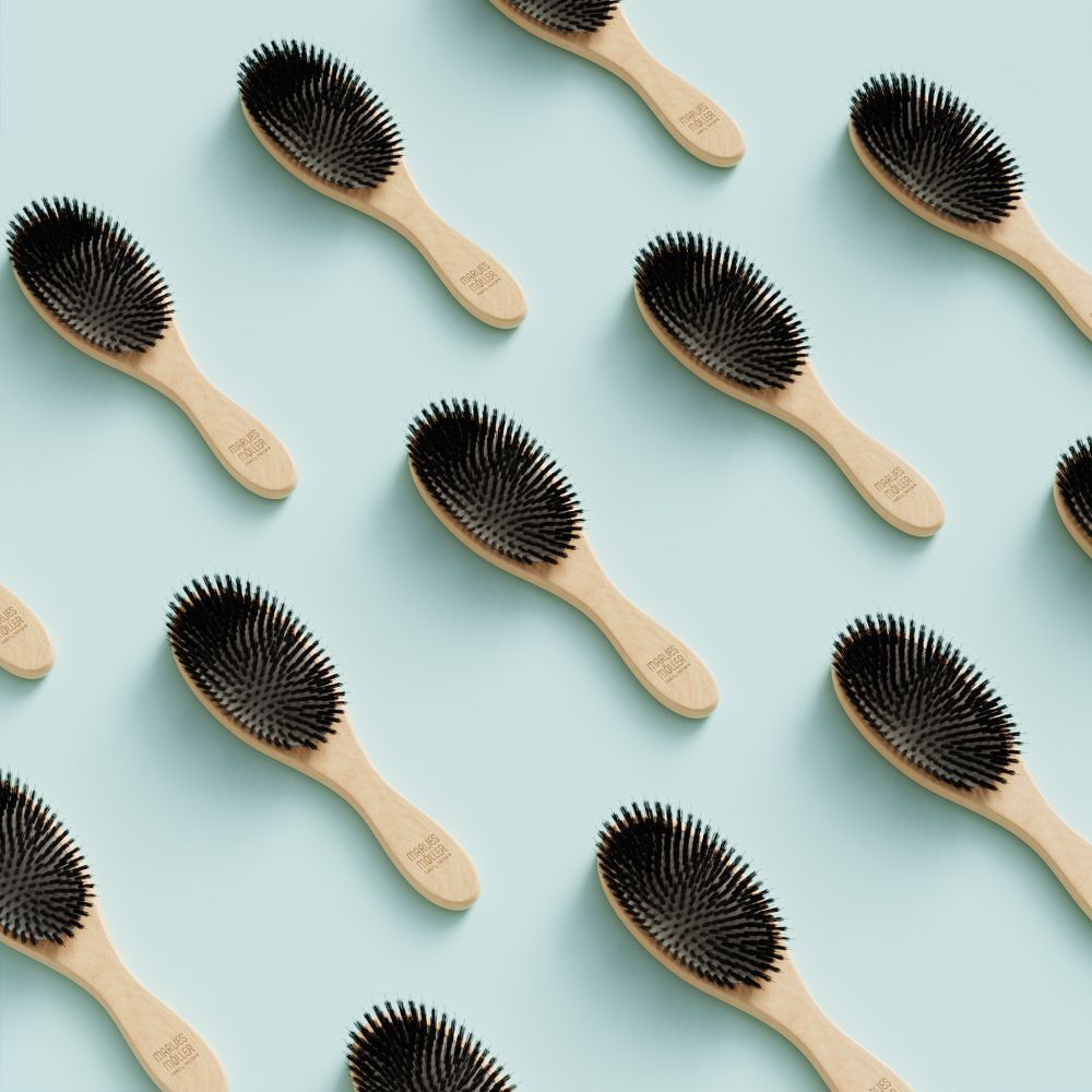 Plusieurs brosses avec manche en bois sur fond bleu clair. Soies noires. "Marlies Möller" sur le manche.