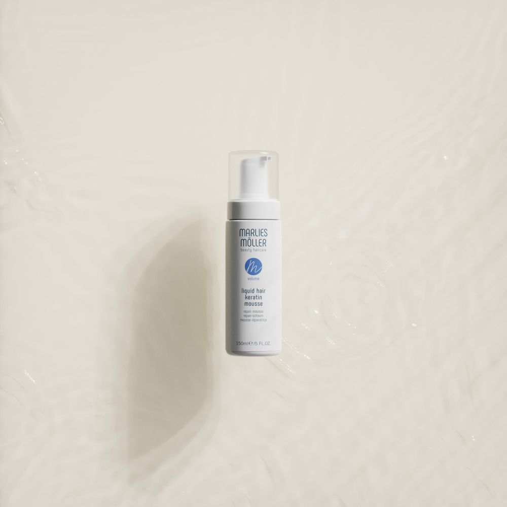 Flacon blanc avec vaporisateur. Inscription: Marlies Möller, Liquid Hair Keratin Mousse. 150ml/5 FL.OZ. Sur fond clair.