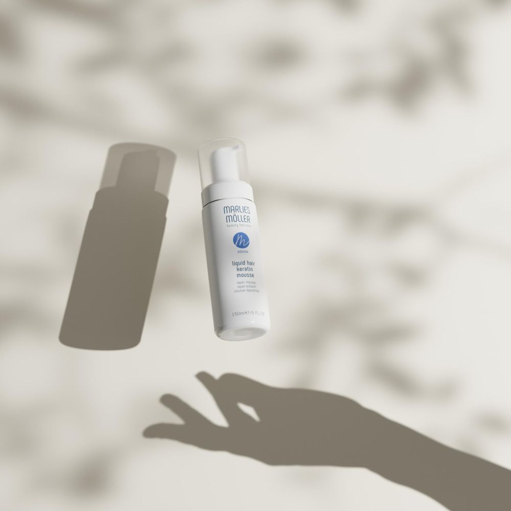 Flacon blanc avec vaporisateur. Inscription: Marlies Möller, Liquid Hair Keratin Mousse. 150ml/5 FL.OZ. Avec des ombres.