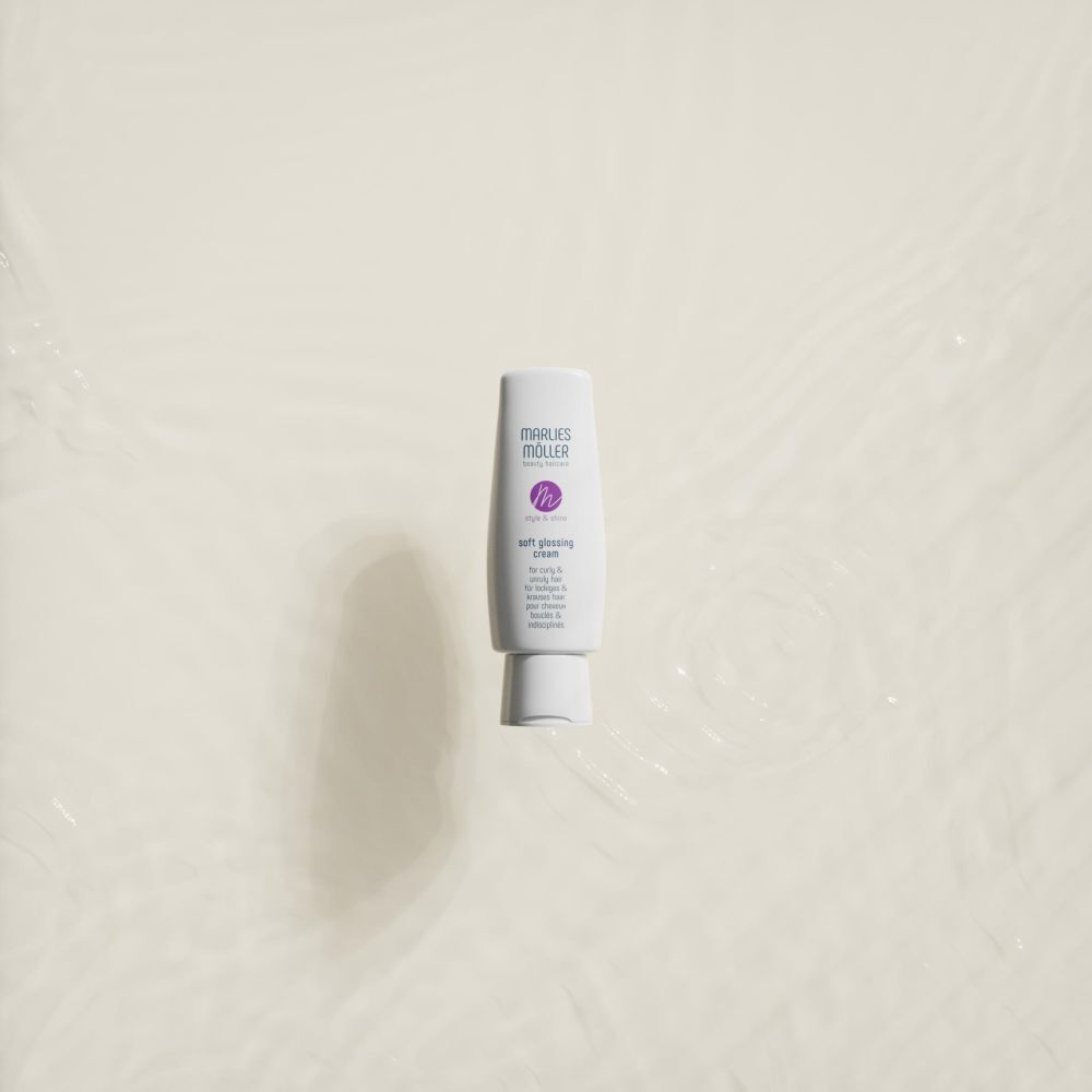 Un tube blanc avec logo et texte violets. Inscription: MÖLLER, Soft Glossing Cream. Sur fond clair.