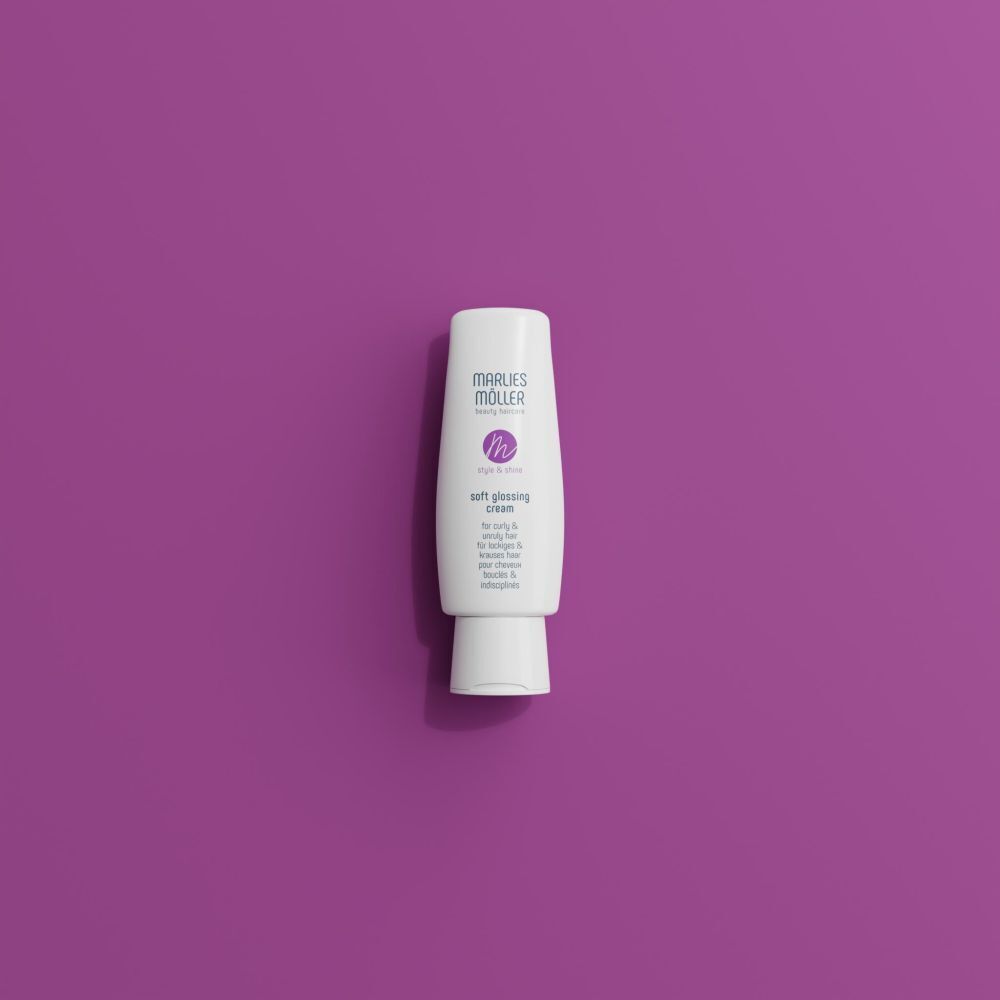 Weiße Tube mit lila Logo und Schriftzug. Aufschrift: Soft Glossing Cream. Auf violettem Hintergrund.