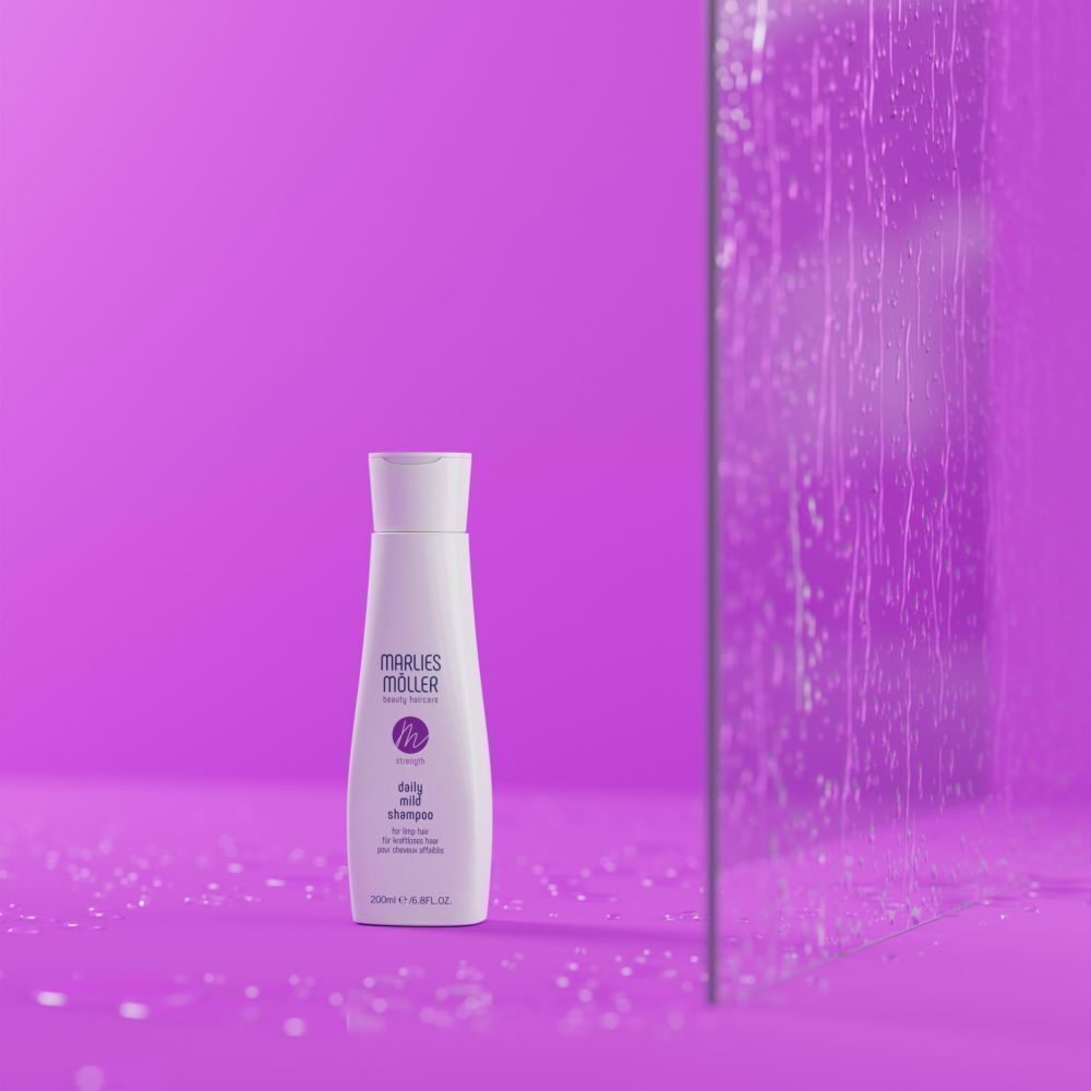 Un flacon blanc avec bouchon blanc devant un fond violet et une paroi de verre. Le flacon porte "Marlies Möller" et "daily mild shampoo".
