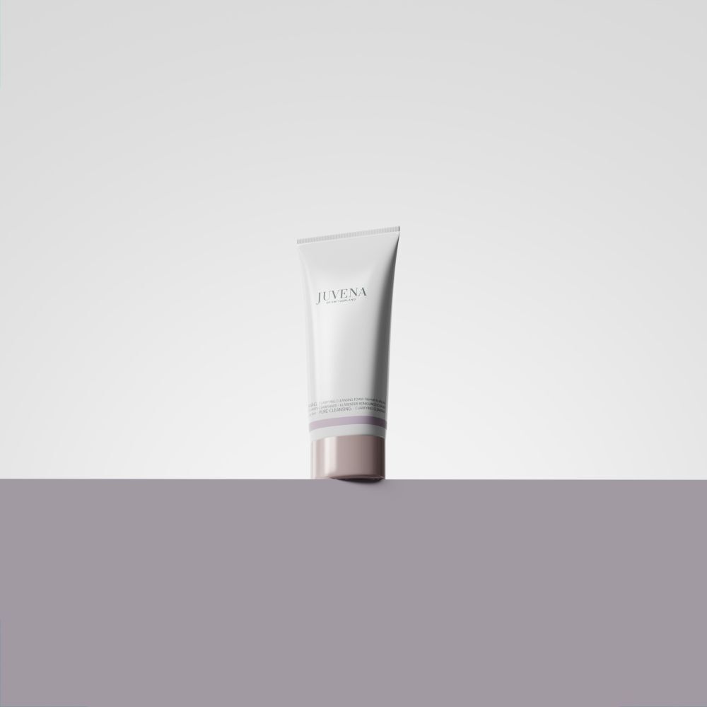 Eine weiße Tube Juvena Clarifying Cleansing Foam auf einem grauen Podest.
