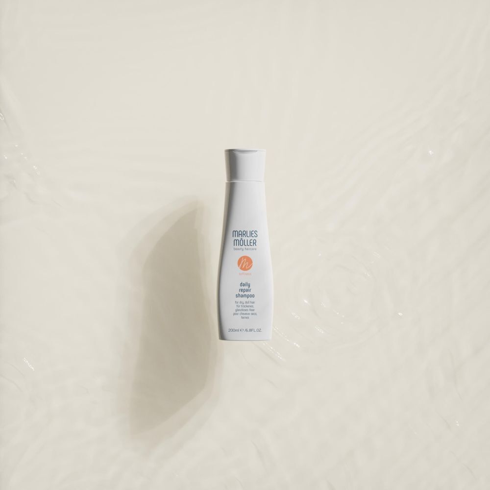 Weiße Flasche mit weißem Deckel. Aufschrift: Marlies Möller, daily repair shampoo. Auf hellem Hintergrund.