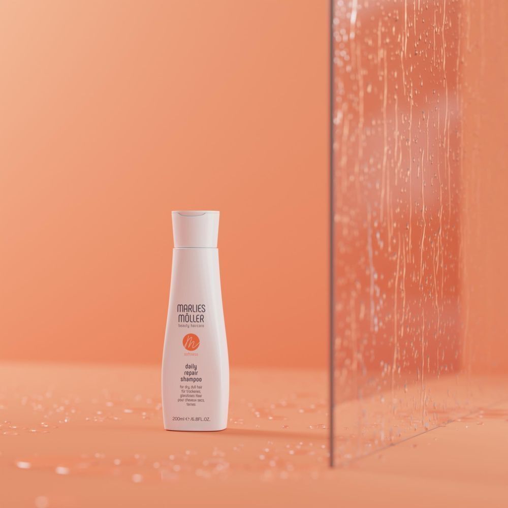 Weiße Flasche mit Klappverschluss. Aufschrift: Marlies Möller, daily repair shampoo. Vor orangefarbenem Hintergrund mit Wassertropfen.