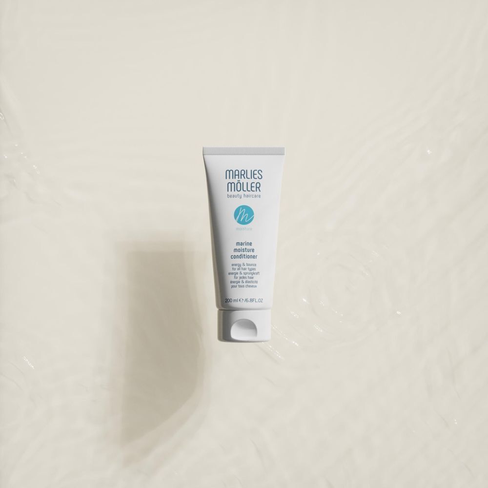 Eine Tube Marlies Möller Marine Moisture Conditioner auf einer hellen, welligen Oberfläche.