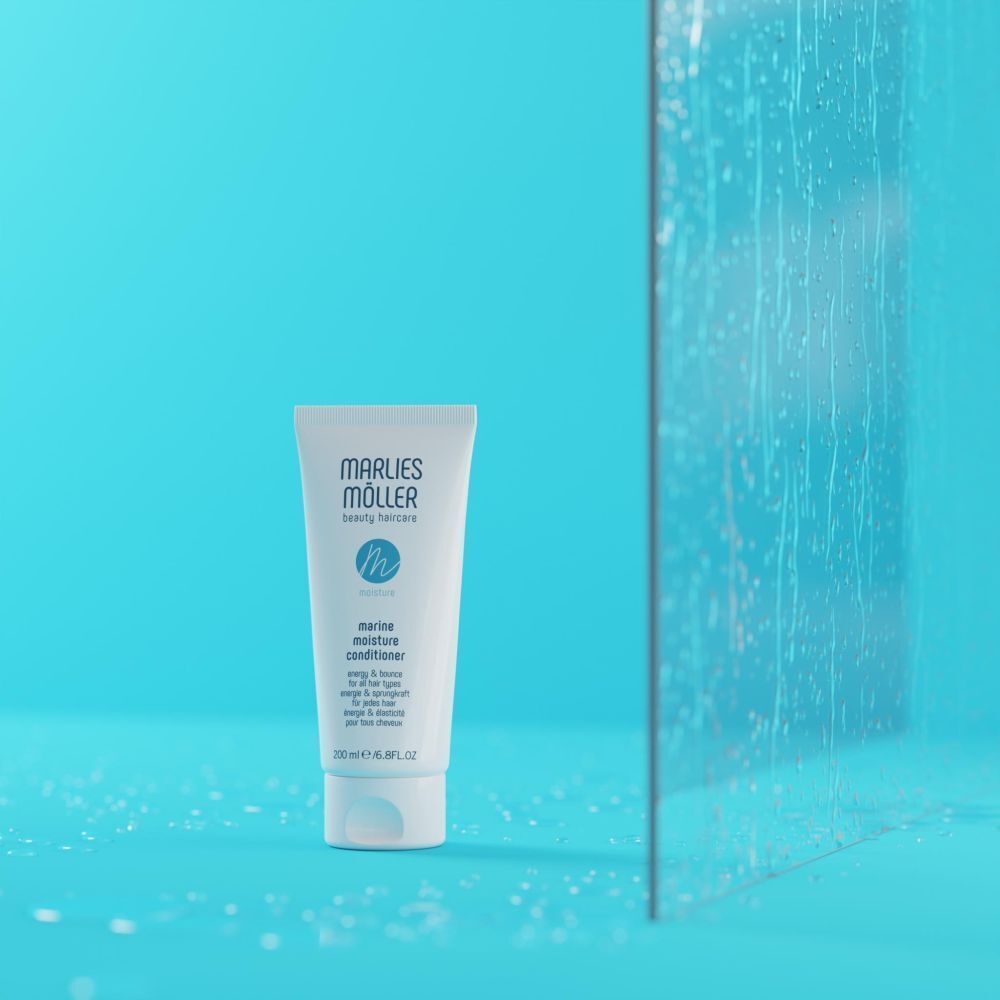 Flacon Marlies Möller Marine Moisture Conditioner devant un fond bleu avec des gouttes d'eau.
