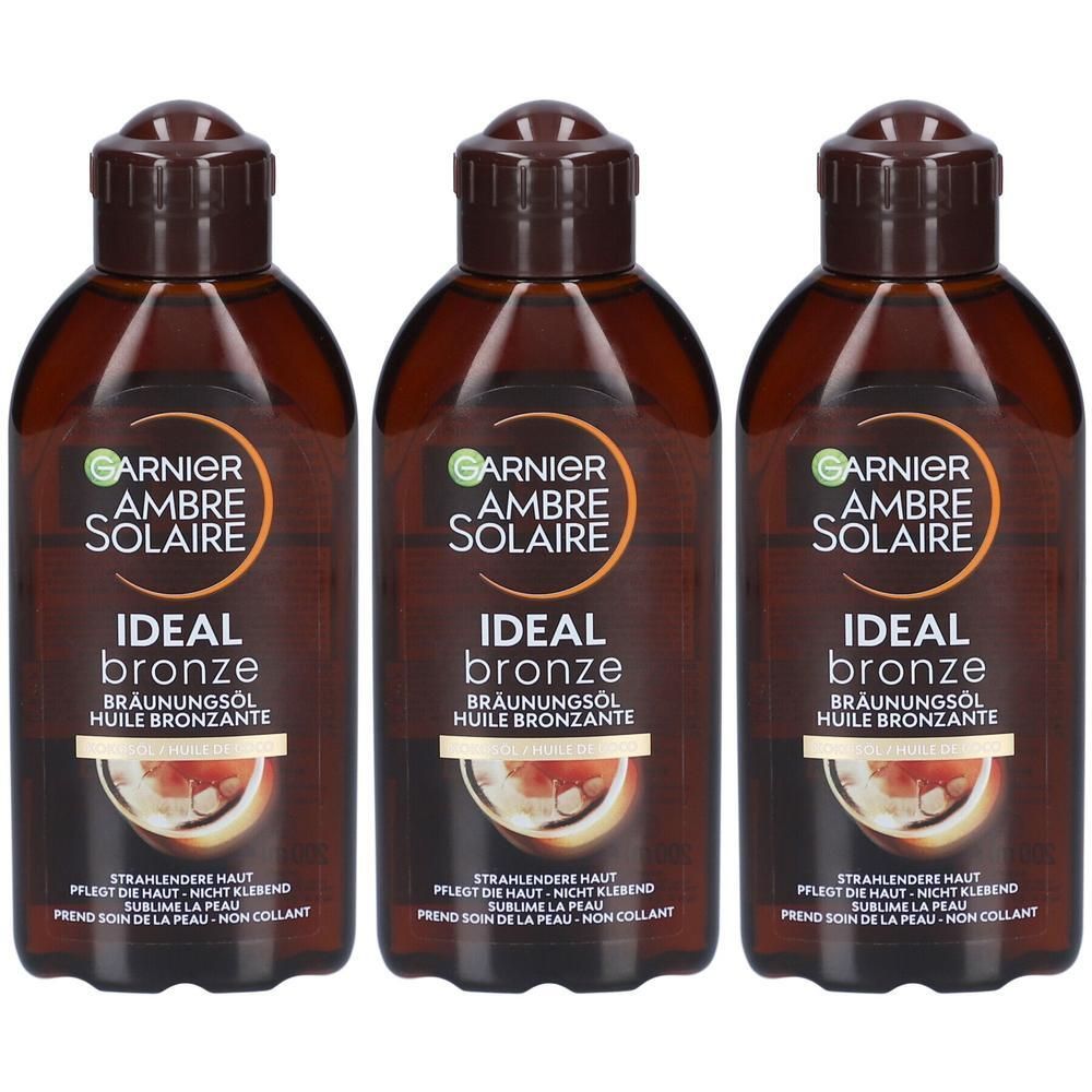 Drei Flaschen Garnier Ambre Solaire Ideal Bronze Bräunungsöl mit braunen Verschlüssen und Etiketten.