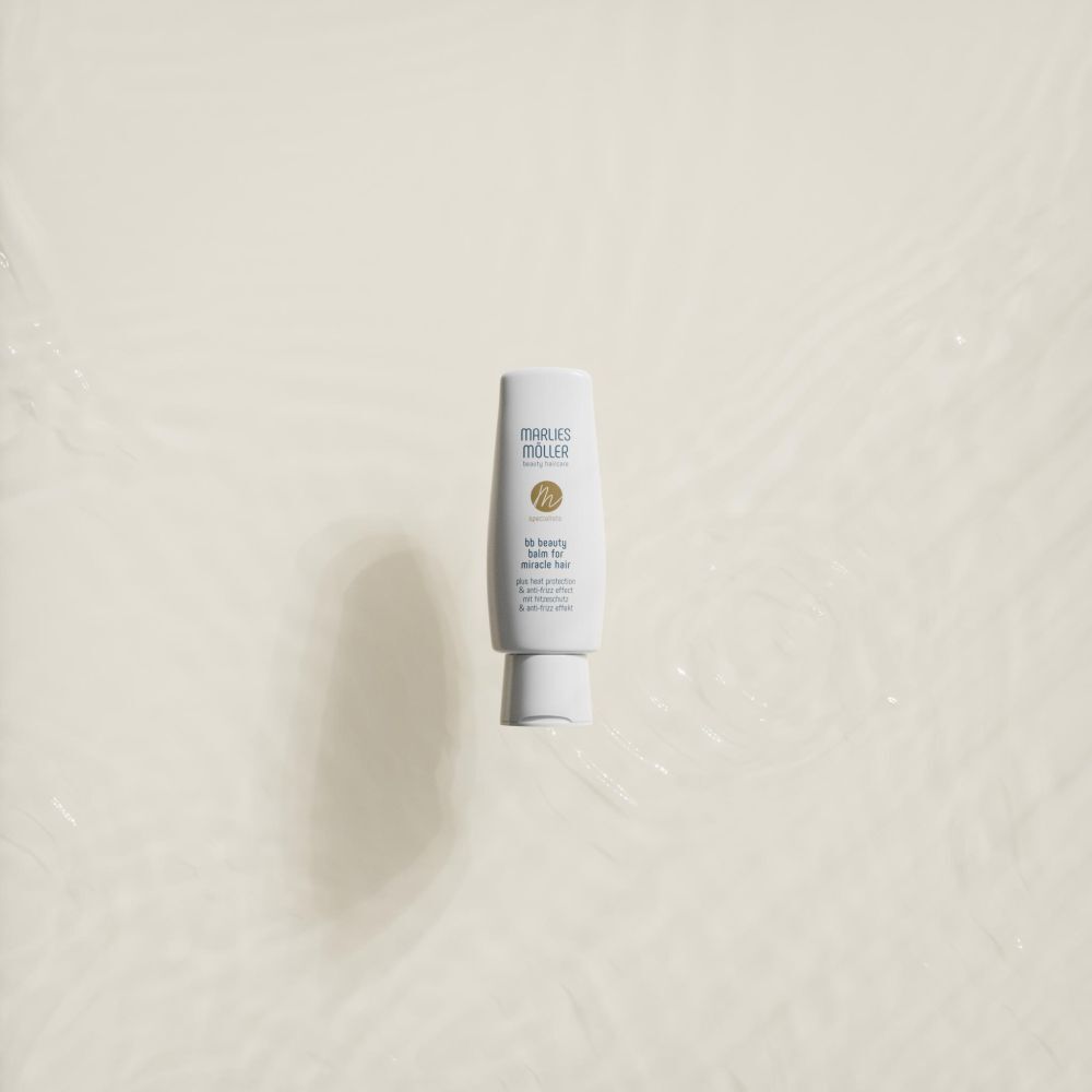 Eine weiße Tube mit blauer Schrift und goldenem Logo. Aufschrift: MÖLLER, bb beauty balm for miracle hair. Im Wasser.