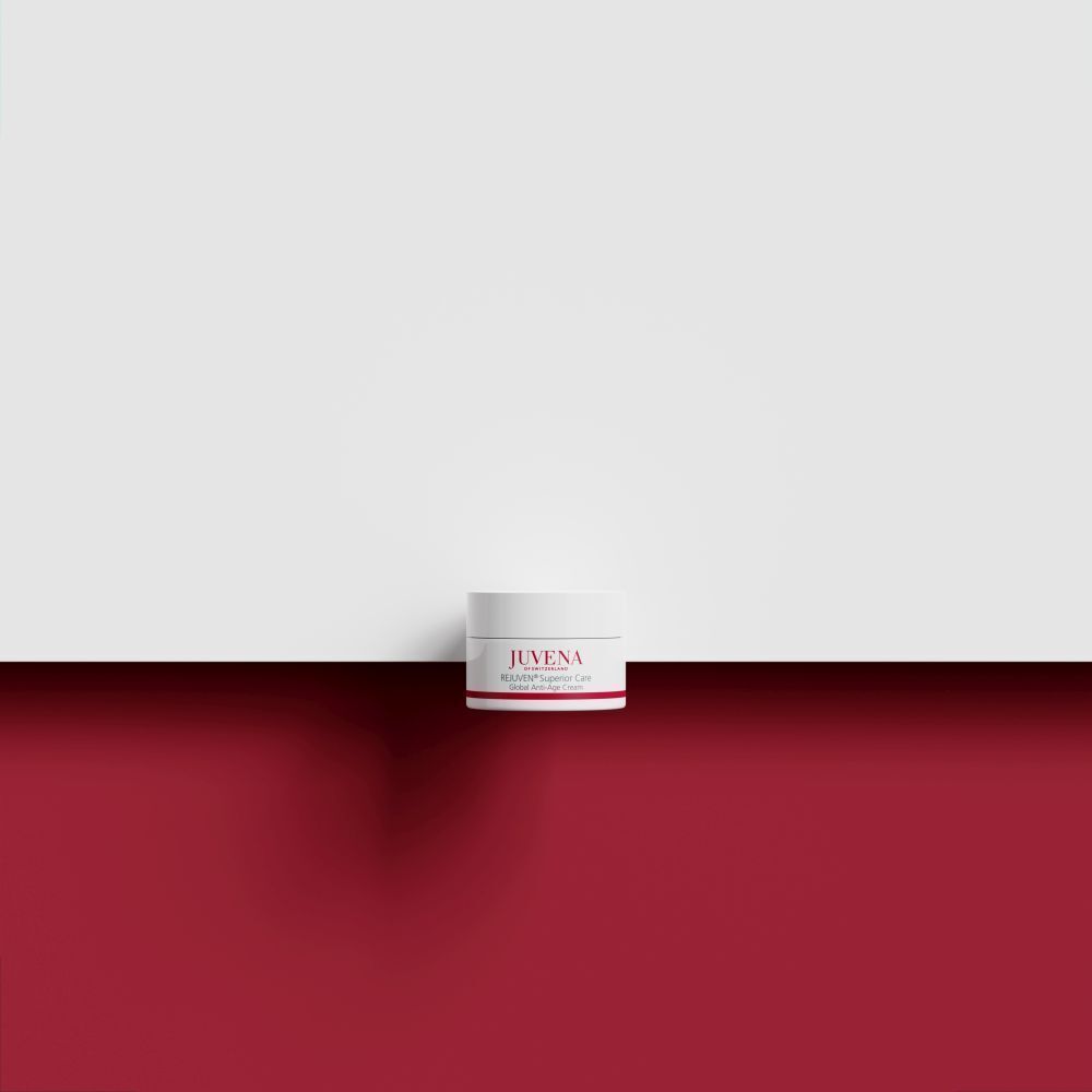 Ein Tiegel JUVENA REJUVEN MEN Global Anti-Age Cream. Weißer Tiegel mit rotem Streifen und Schriftzug. Auf rotem Untergrund.