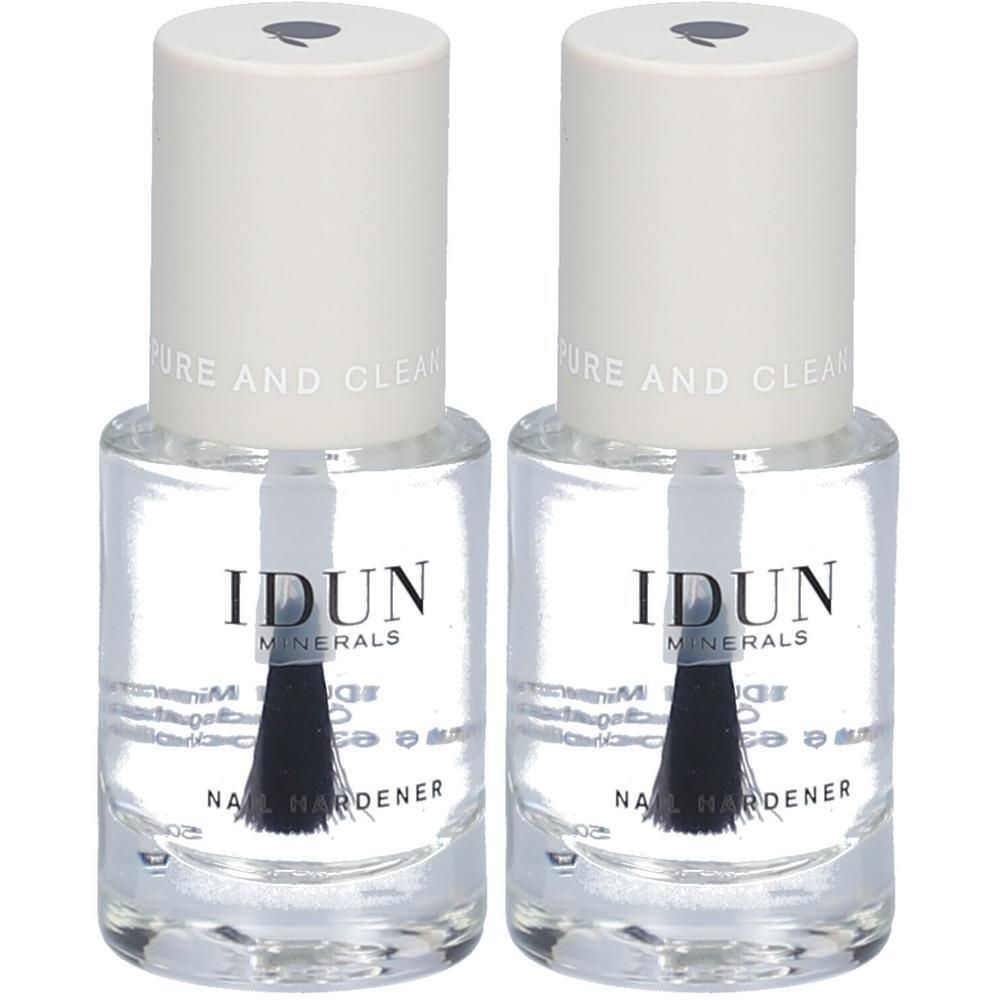 Deux flacons de durcisseur pour ongles IDUN Minerals. Liquide clair dans des flacons en verre avec des bouchons blancs et un pinceau. Inscription : Nail Hardener.