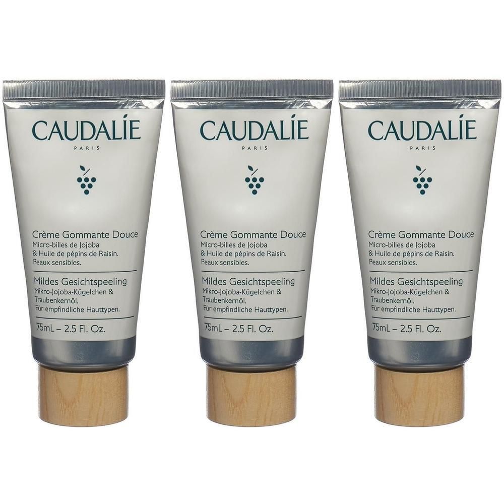 Drei Tuben CAUDALIE Crème Gommante Douce. Weiße Tuben mit grauen Deckeln und Holzsockeln. Text und Logo in Grün.