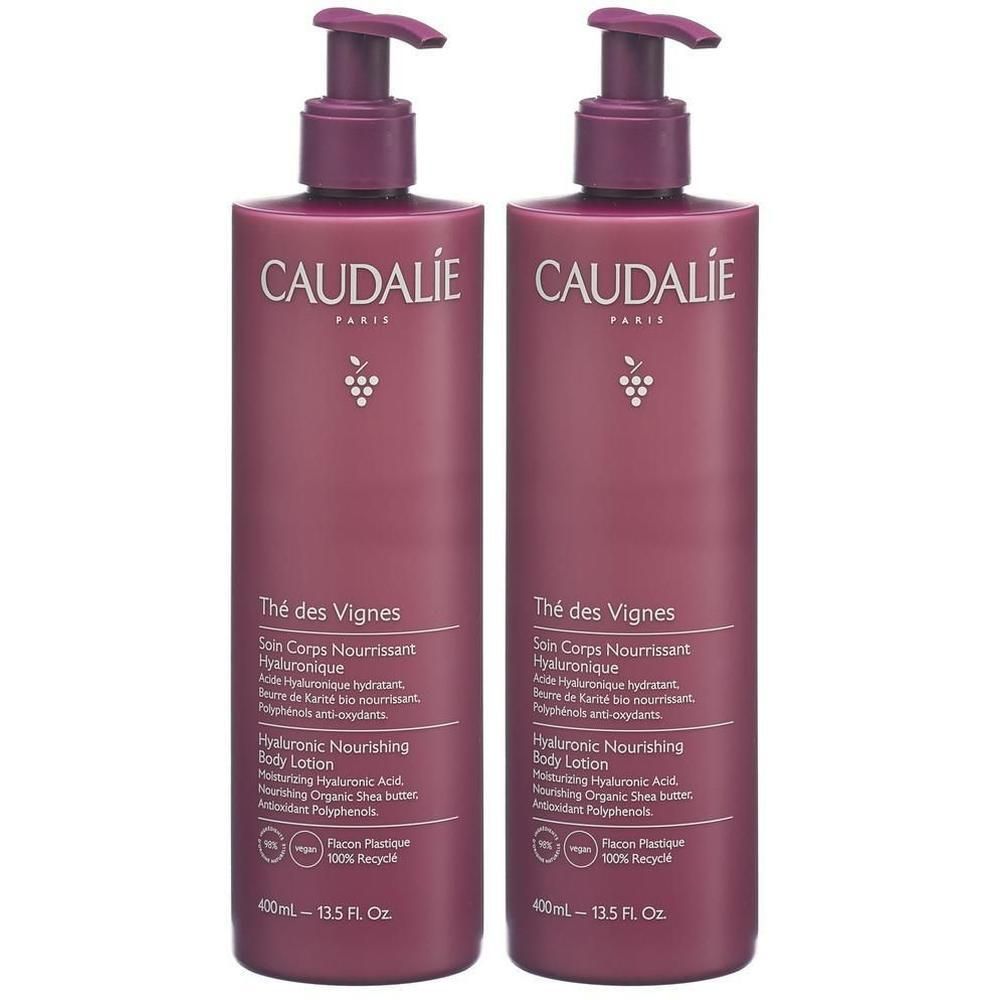 Zwei Flaschen Körperlotion mit Pumpverschluss. Aufschrift CAUDALIE, Thé des Vignes, Hyaluronic Nourishing Body Lotion. Flaschenfarbe: Pflaume.