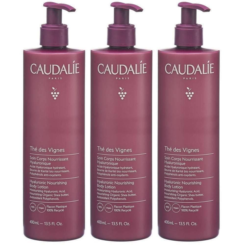Drei Flaschen CAUDALIE Thé des Vignes Bodylotion mit Pumpverschluss. Flaschen in dunklem Rosa mit weißer Schrift und Trauben-Logo.