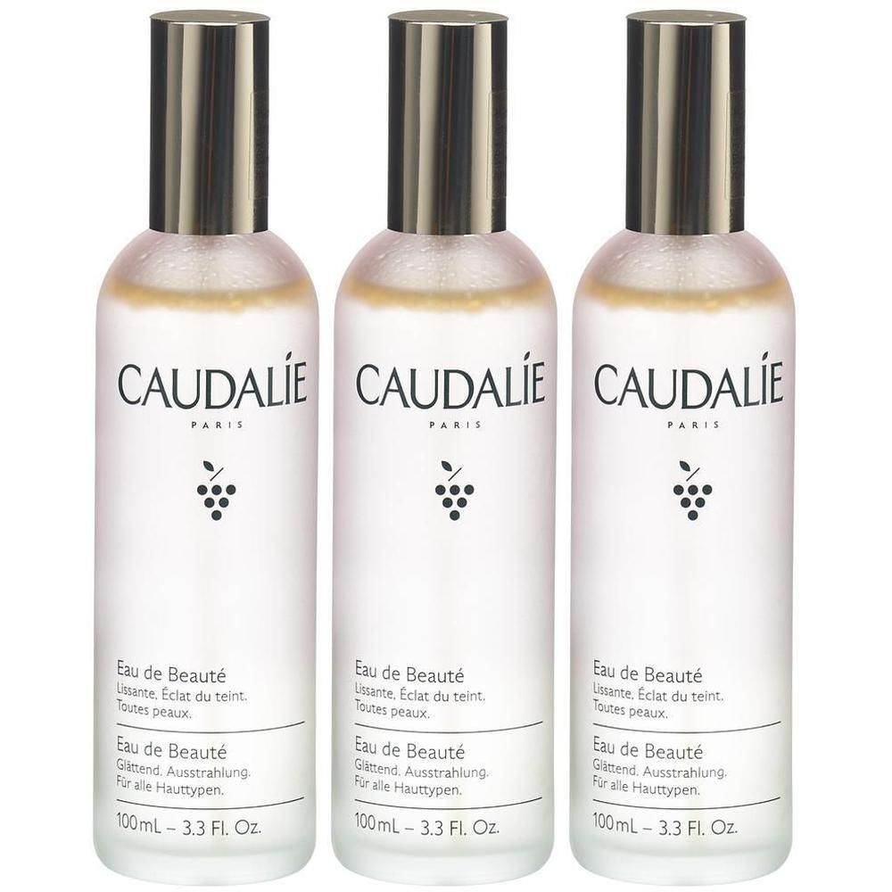 Drei Flaschen mit silbernen Deckeln. Aufschrift CAUDALIE PARIS, Eau de Beauté. Weiße Etiketten mit Text und Trauben-Logo.