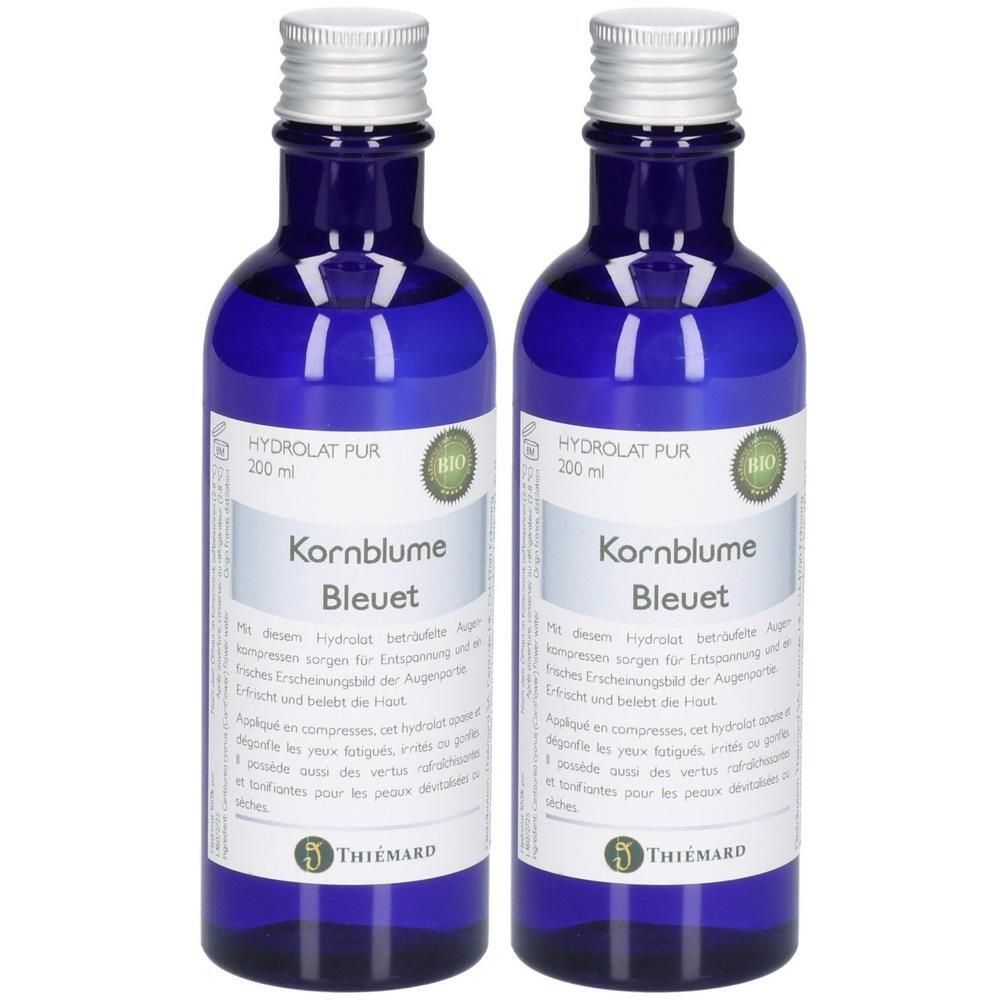 Zwei blaue Glasflaschen mit silbernen Verschlüssen, gefüllt mit Kornblumenwasser, "HydroLat PUR 200 ml" und "BIO"-Siegel.