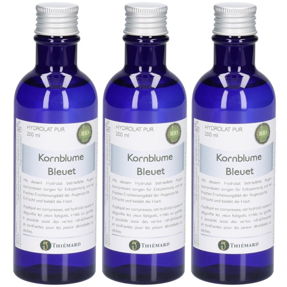 Drei blaue Glasflaschen mit silbernen Verschlüssen, die Kornblumenhydrolat zeigen.
