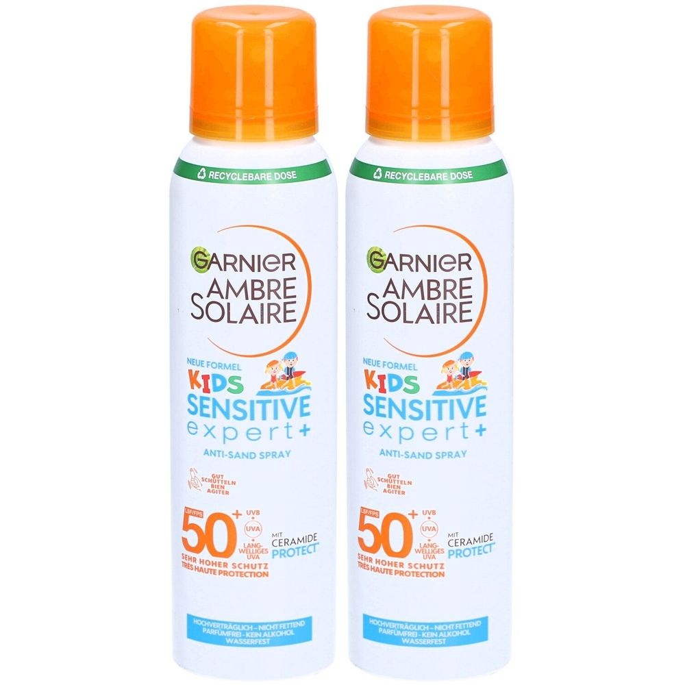 Zwei Sprays von Garnier Ambre Solaire Kids Sensitive Expert+ SPF50+. Weiße Flaschen mit orangefarbenen Deckeln. Text: Anti-Sand Spray, 50, Ceramide Protect.