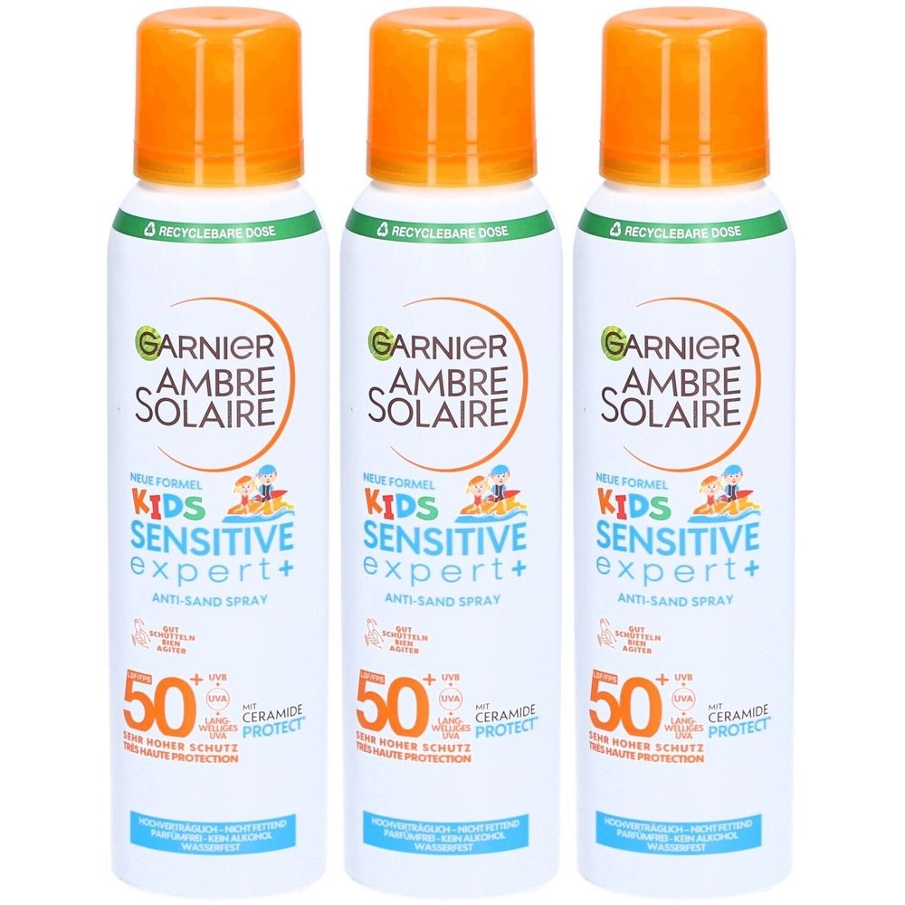 Drei Sprays von Garnier Ambre Solaire Kids Sensitive Expert+ SPF50+. Weiße Flaschen mit orangefarbenen Deckeln. Text: Anti-Sand Spray.