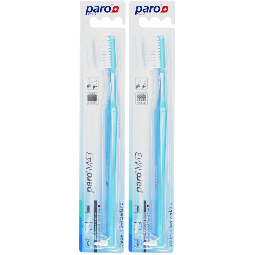 Deux brosses à dents en emballage blister. Manches bleus, poils blancs. Inscription : paro M43, Made in Switzerland.
