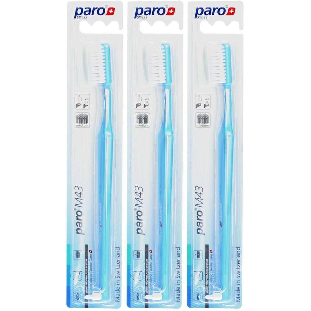 Trois brosses à dents dans des emballages transparents. Manches bleus, soies blanches. Marque : paro. Modèle M43. Fabriqué en Suisse.