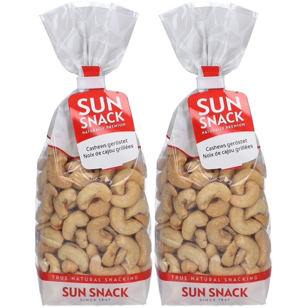 Deux sachets de SUN SNACK noix de cajou. Sacs transparents avec étiquette rouge. Texte: Cashews geröstet, Noix de cajou grillées.