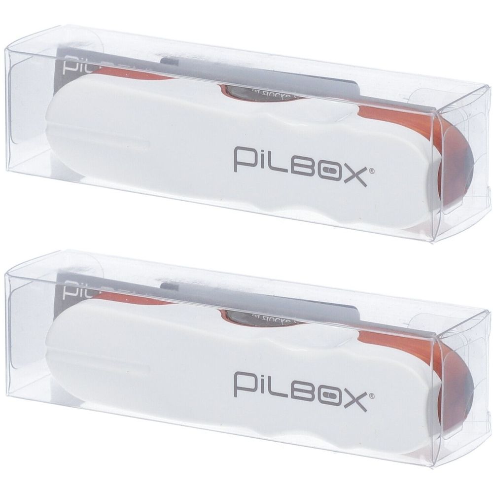 Zwei Tablettenschneider in transparenten Kunststoffboxen. Weißes Gehäuse mit rotem Einsatz und dem Schriftzug PILBOX.