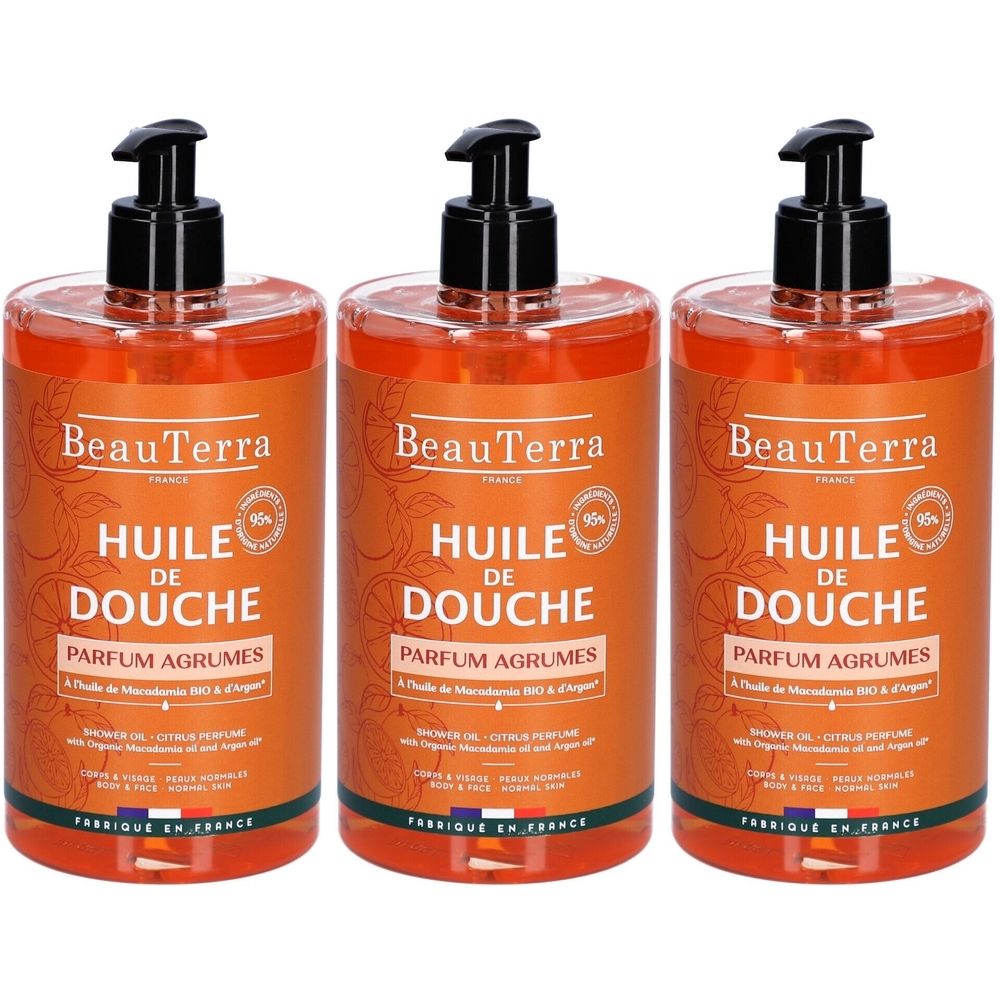 Trois flacons d'huile de douche avec pompe noire. Inscription: BeauTerra, HUILE DE DOUCHE, PARFUM AGRUMES. Liquide orangé.