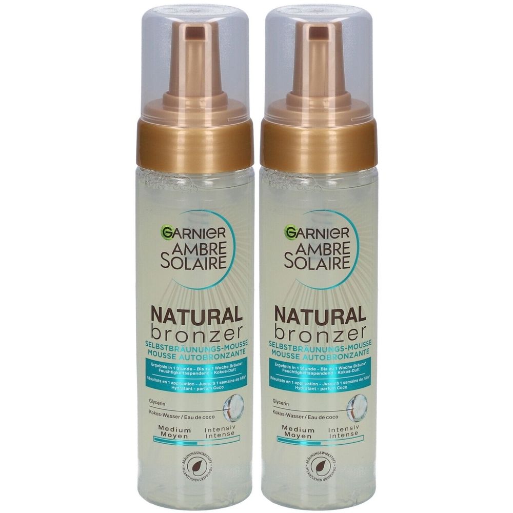Deux flacons de mousse autobronzante Garnier Ambre Solaire Natural Bronzer. Flacons transparents avec bouchons dorés et inscriptions.