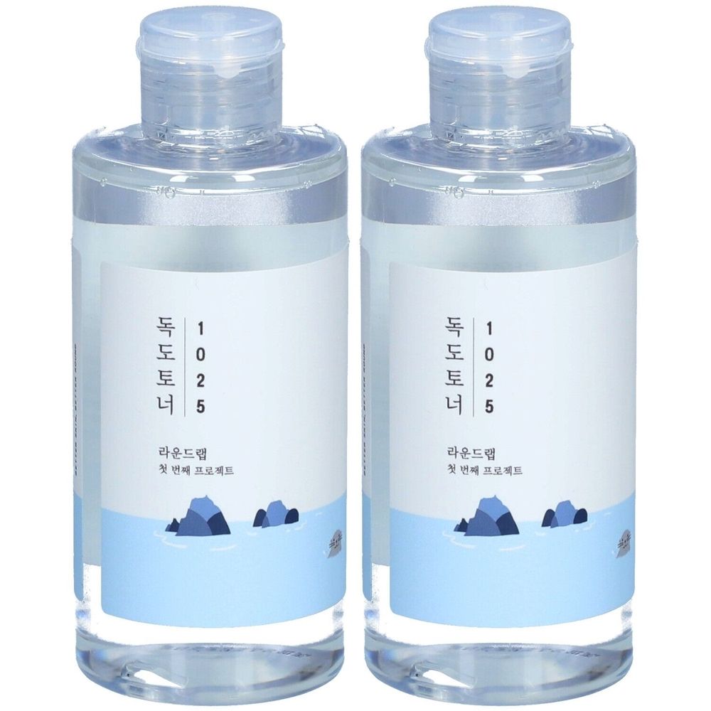 Deux flacons transparents avec étiquette blanche et motif bleu. L'étiquette porte l'inscription coréenne "Dokdo Toner".