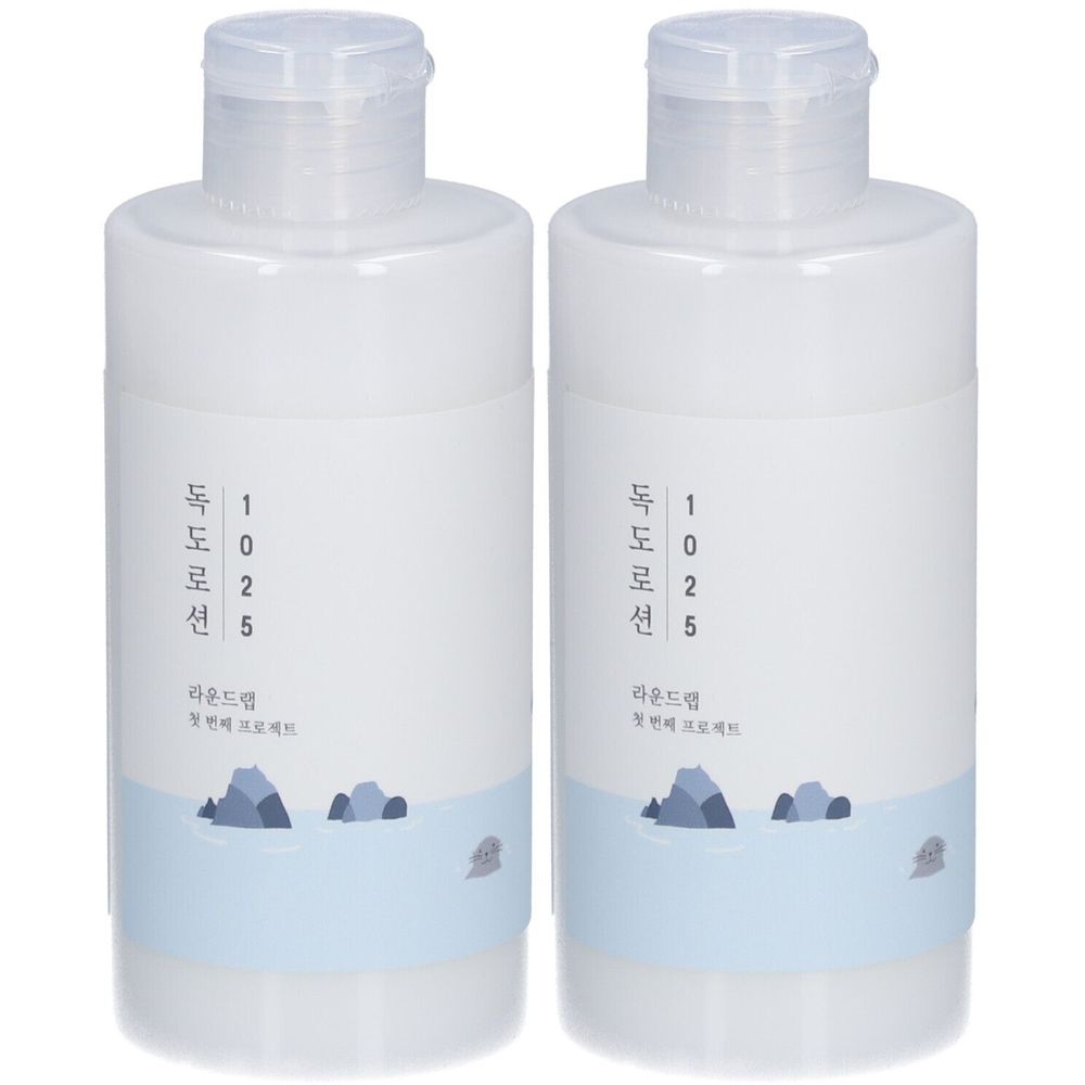 Deux flacons blancs avec bouchons transparents. Caractères coréens et bande bleue avec rochers. Lotion pour le visage.