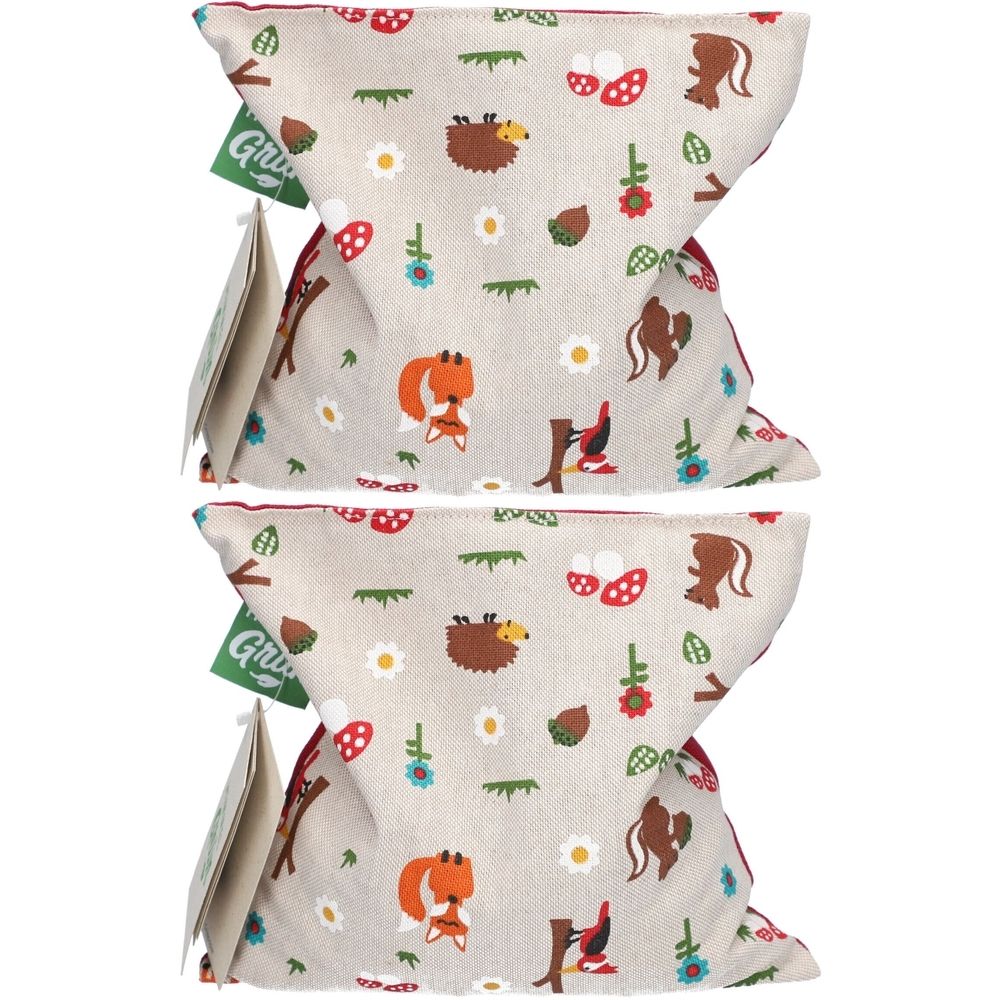 Zwei Kirschkernkissen mit Waldtier-Design. Beige Stoff mit Fuchs, Igel, Pilzen und Blumen. Grün-Etikett mit Logo.