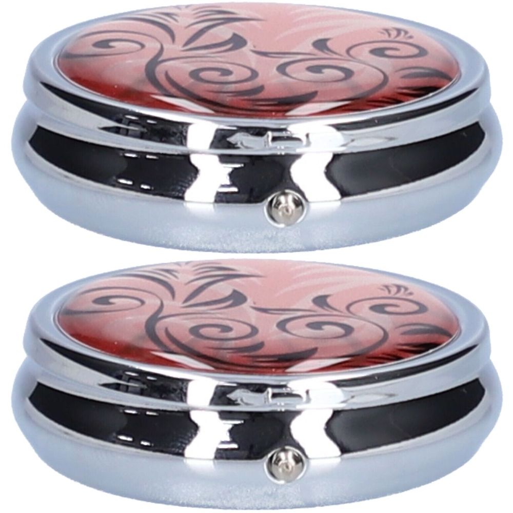 Deux piluliers ronds, corps argenté, couvercle rose à motifs floraux noirs. Chaque boîte est munie d'un fermoir.