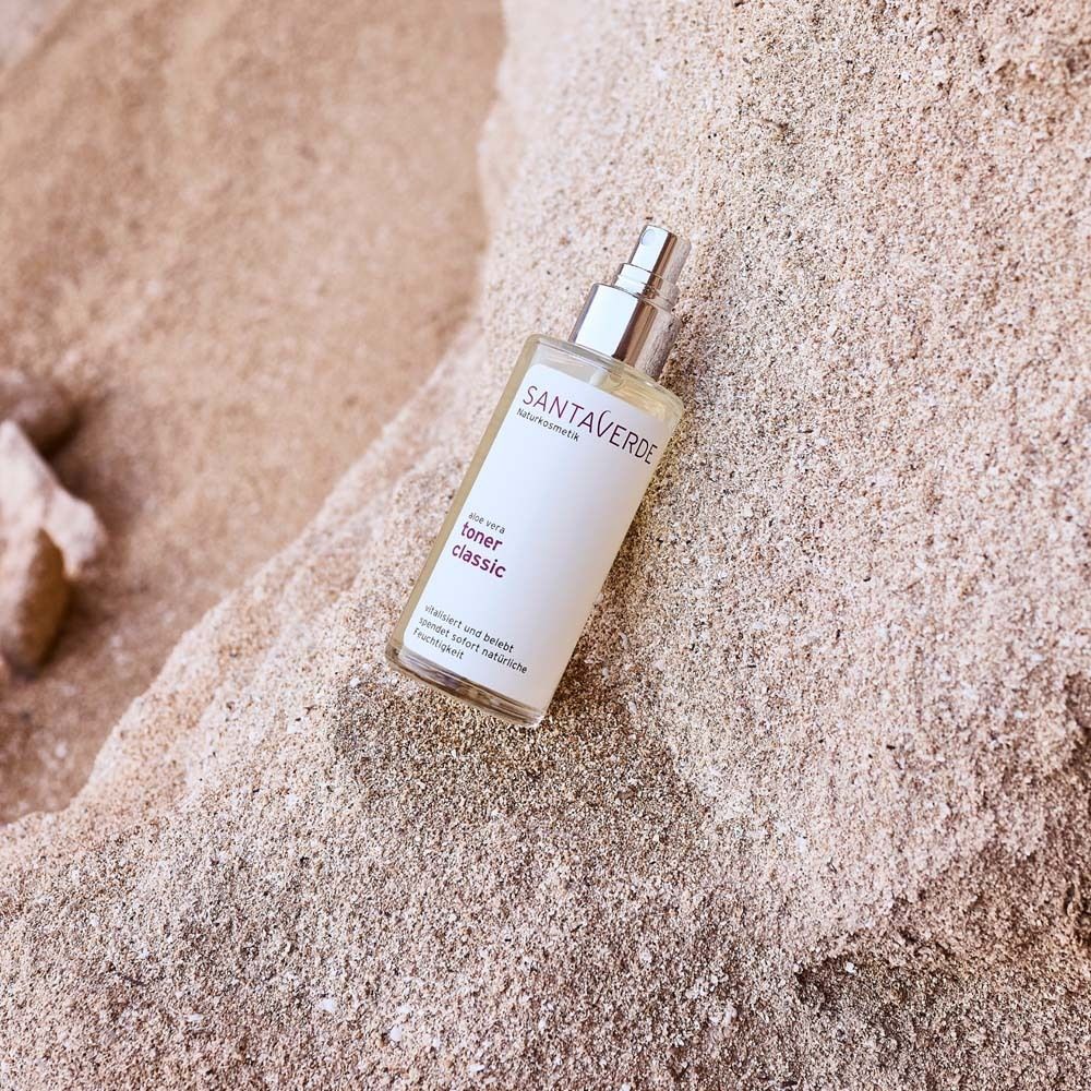 SANTAVERDE Aloe Vera Toner Classic. Flacon en verre avec vaporisateur sur sable. Étiquette du produit visible.