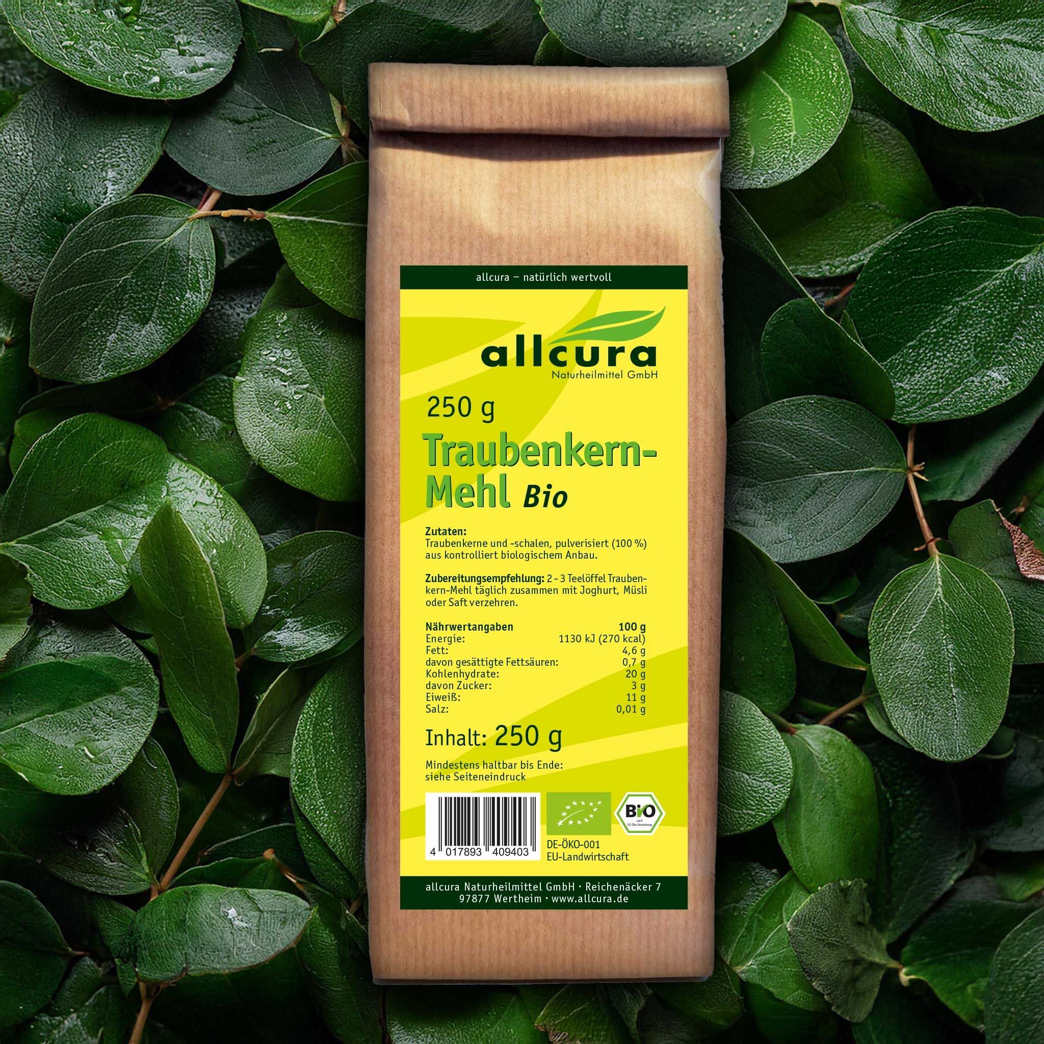 Sac en papier brun avec étiquette jaune, entouré de feuilles vertes. Inscription : Traubenkern-Mehl Bio, 250 g. Label bio.