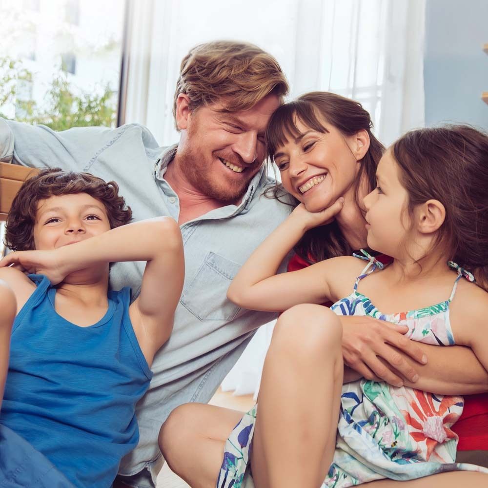 Familie im Wohnzimmer. Kinder und Eltern lächeln. Gemütliche Atmosphäre.