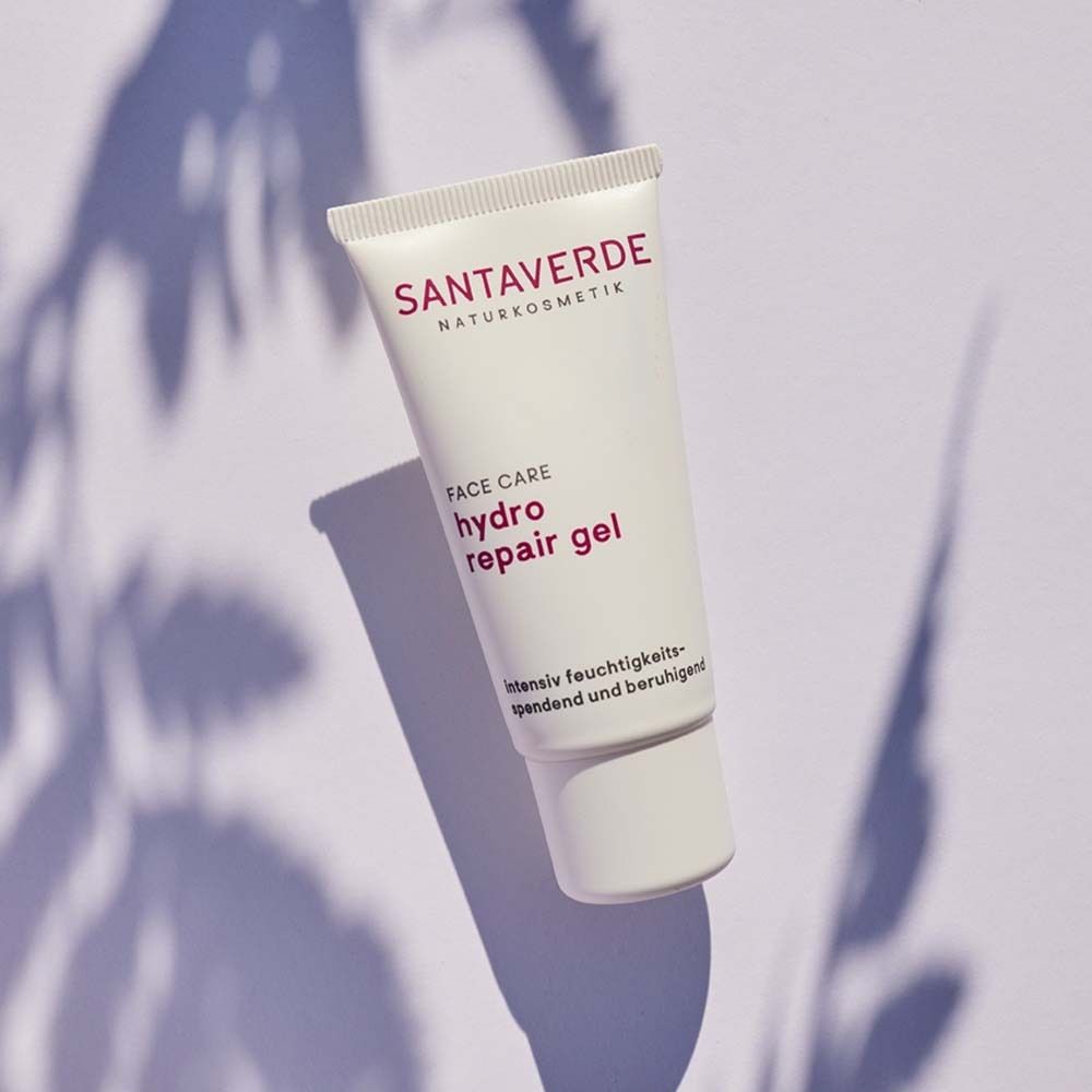 Tube blanc avec logo SANTAVERDE et nom du produit. Ombres de feuilles en arrière-plan.