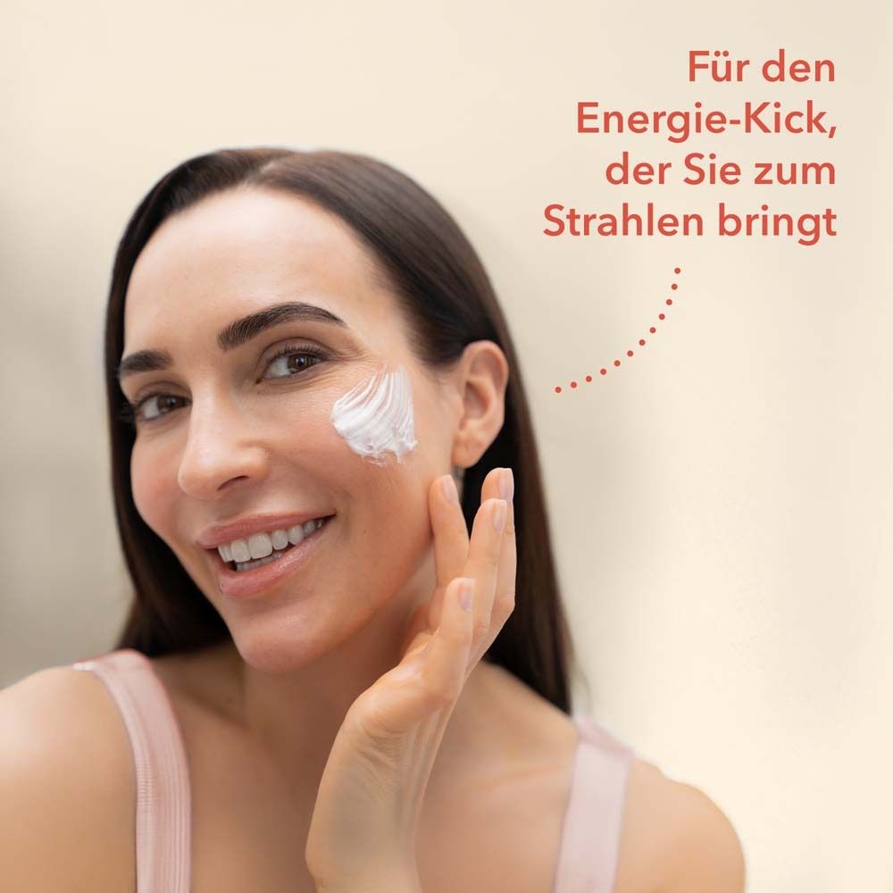 Frau mit aufgetragener Creme auf der Wange. Text: Für den Energie-Kick, der Sie zum Strahlen bringt.