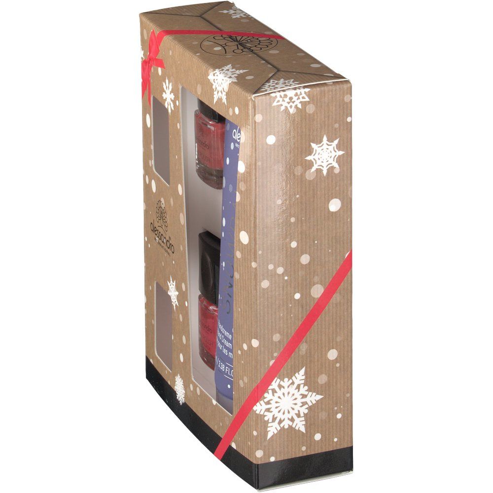 Vue latérale de l'emballage du coffret cadeau. Tube de crème pour les mains et flacons de vernis à ongles visibles à travers les fenêtres. Emballage avec flocons et ruban rouge.