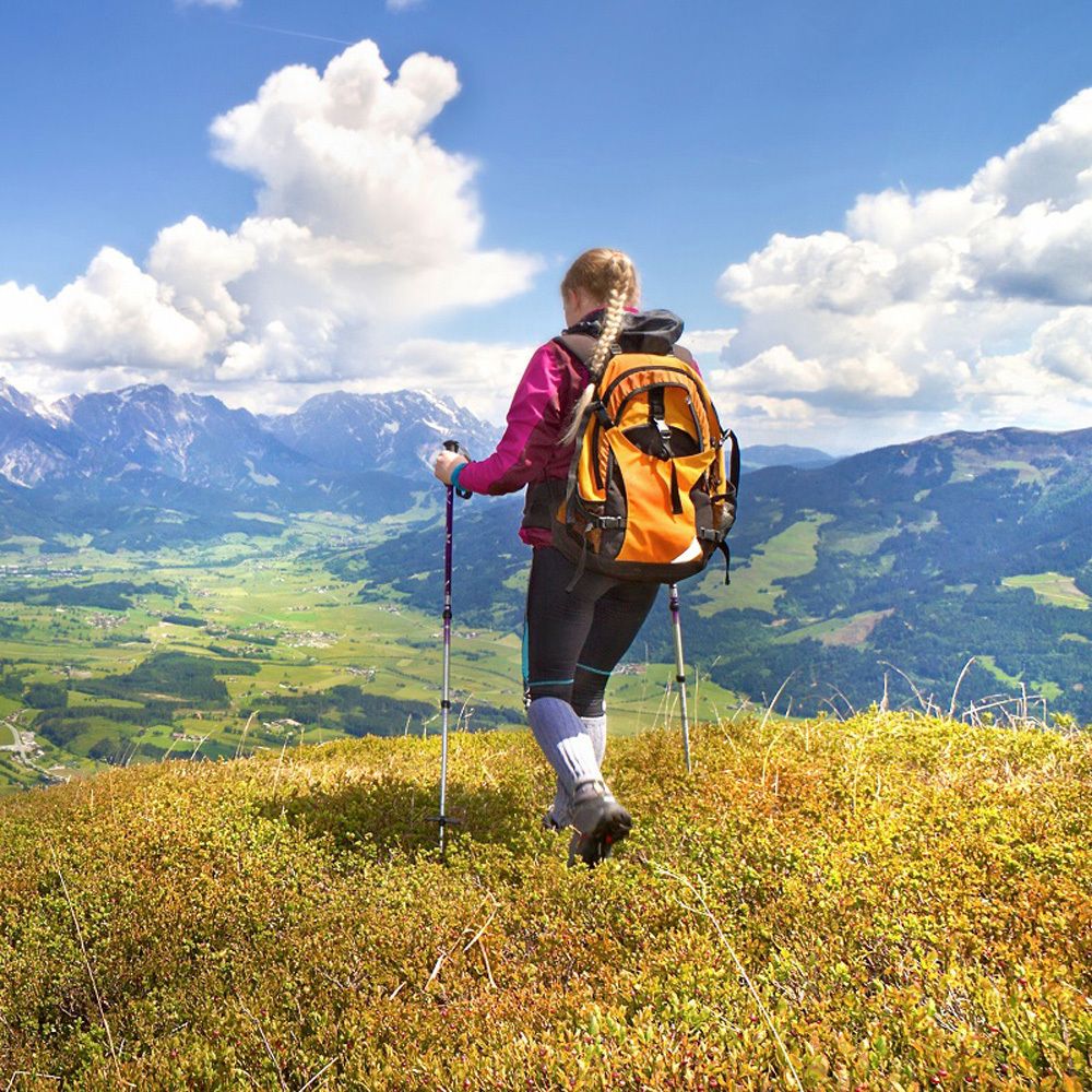Frau mit Rucksack wandert in den Bergen. Blick auf Berge und Landschaft.