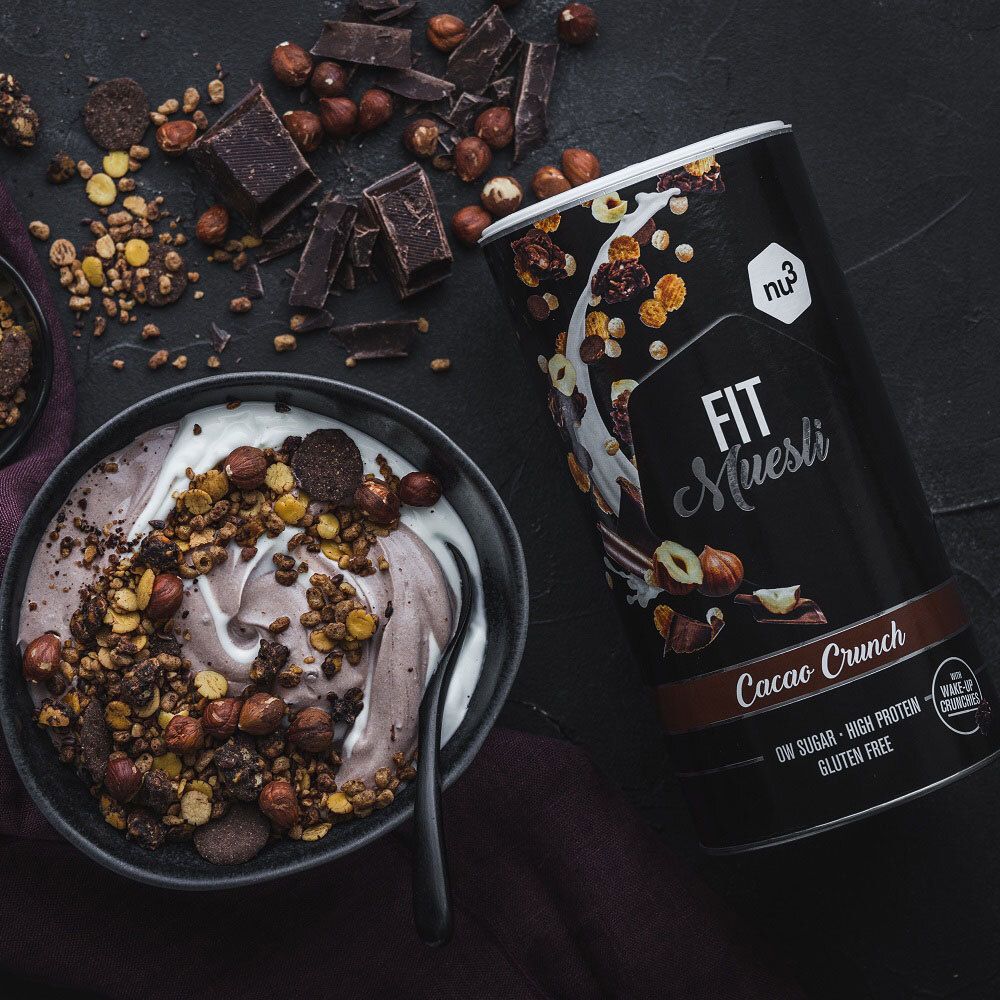 Schwarze Schale mit Müsli, Joghurt, Haselnüssen, Schokolade. Dose nu3 Fit Müsli Cacao Crunch daneben.