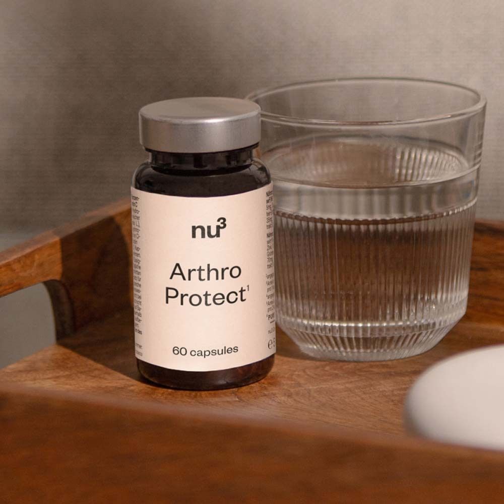 Braune Tablettenflasche mit schwarzem Deckel. Aufschrift: nu3 Arthro Protect, 60 Kapseln. Daneben Glas Wasser.