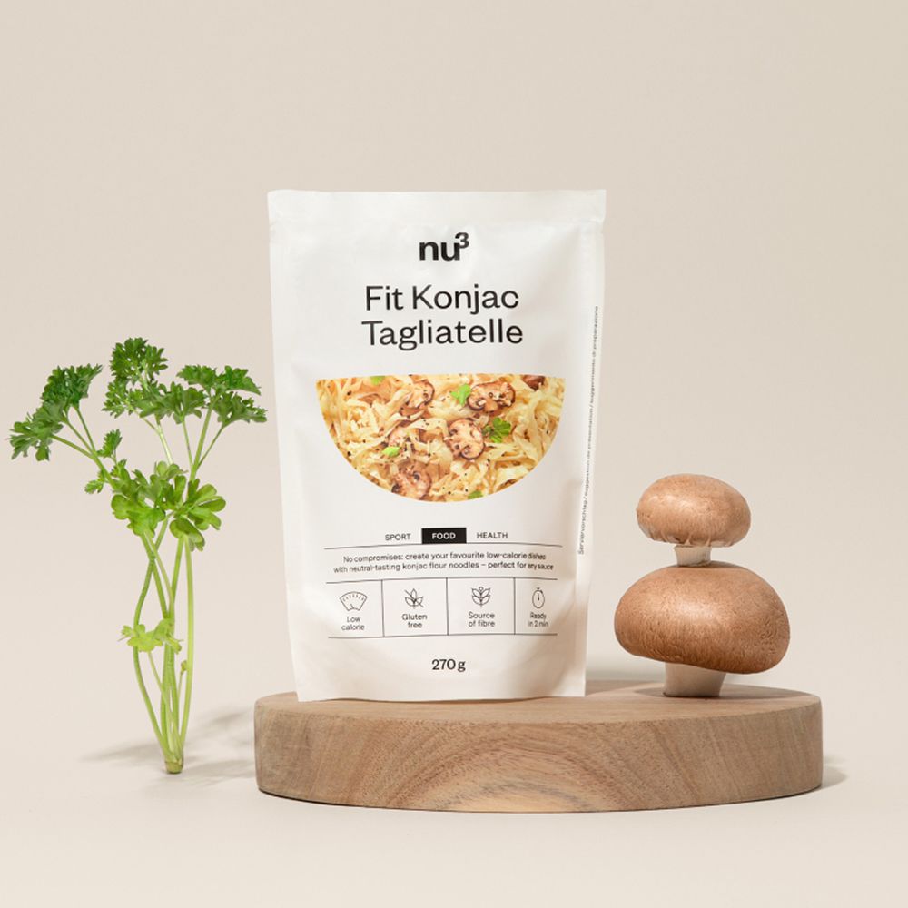 Eine Packung nu3 Fit Konjak-Tagliatelle (270g) auf einem Holzpodest, dekoriert mit Petersilie und Champignons.