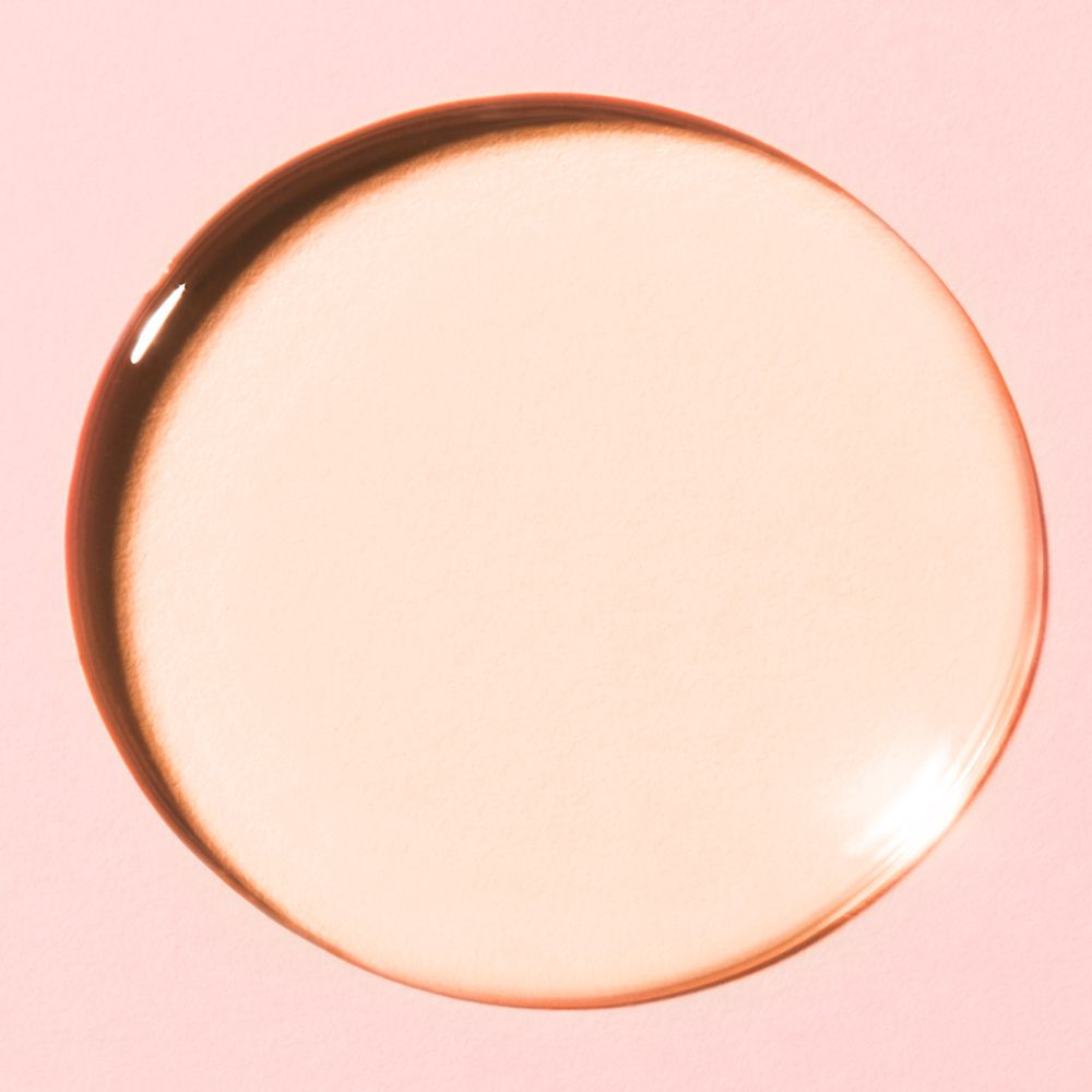 Une goutte circulaire de liquide rose sur fond rose. La goutte a un bord plus foncé.