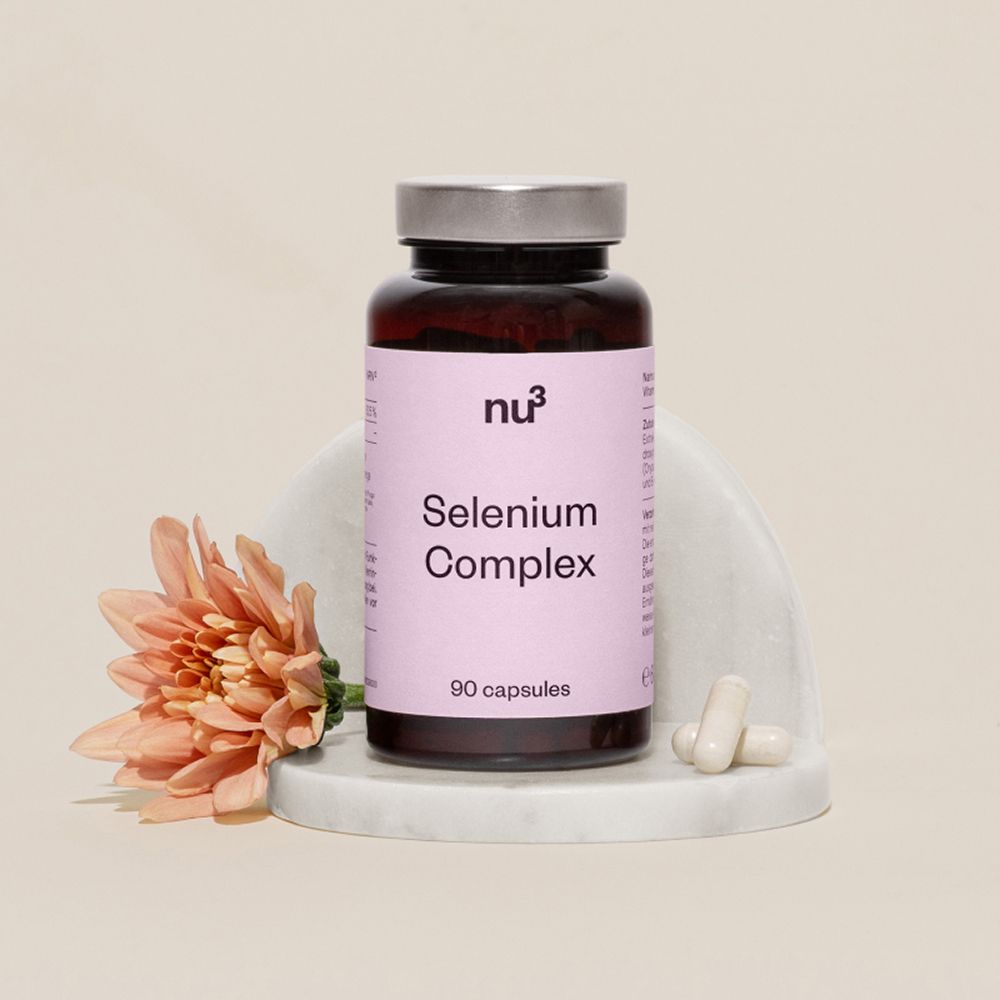 Flacon de nu3 Sélénium Complexe sur socle en marbre avec fleur et gélules.