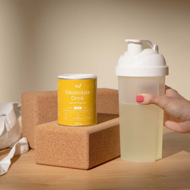 Dose nu3 Elektrolyte Drink Zitrone neben einem Shaker mit Elektrolytgetränk.