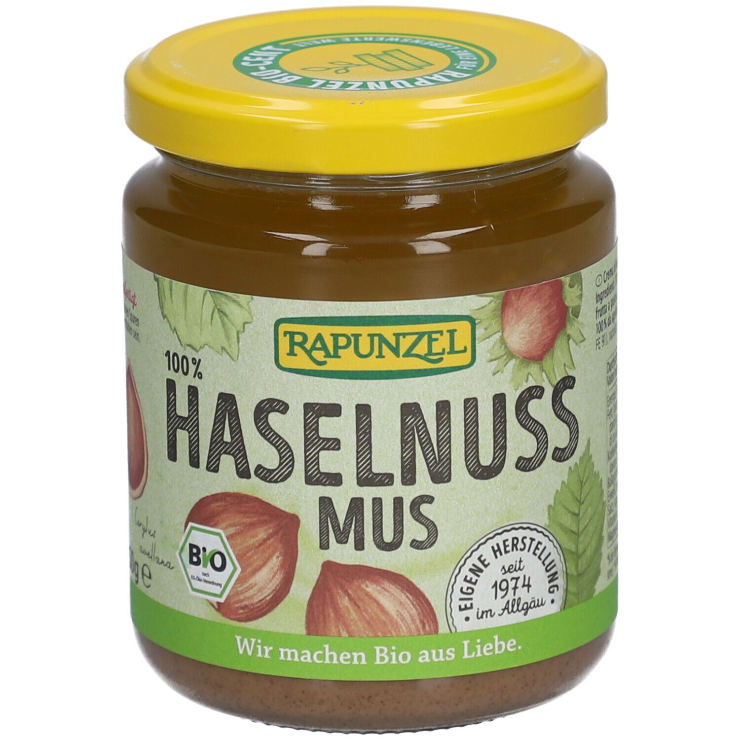 Glas mit Haselnussmus. Gelber Deckel, grüne und braune Etiketten. Aufschrift: RAPUNZEL, BIO, Haselnuss Mus.